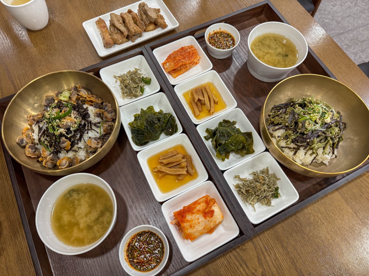 제주 어장군의 고사리비빔밥과 꼬막비빔밥 한상차림, 달래양념과 반찬이 함께 차려진 모습