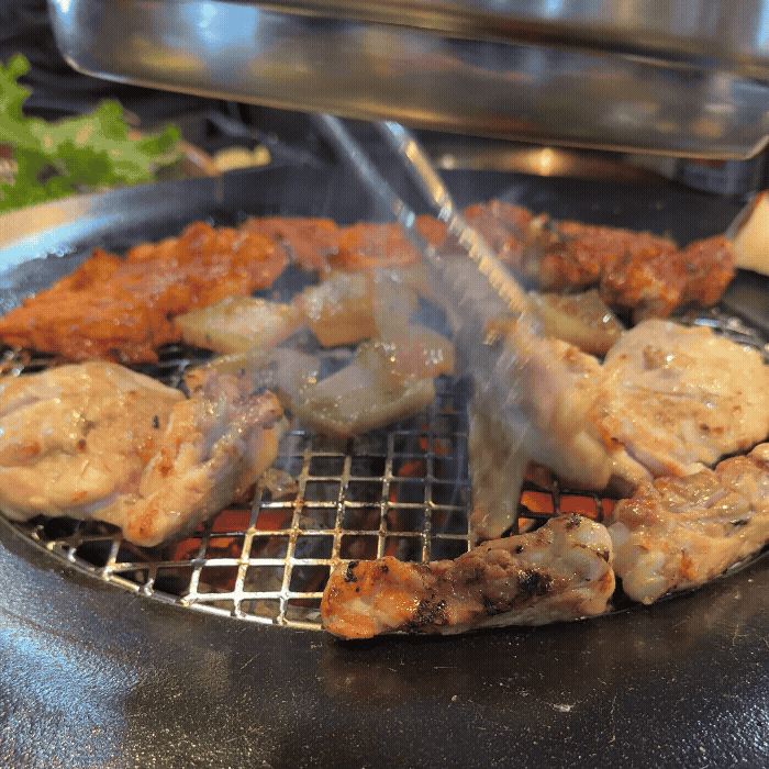 서서방숯불닭갈비에서 초벌된 제주 닭갈비를 숯불에 굽고 있는 장면